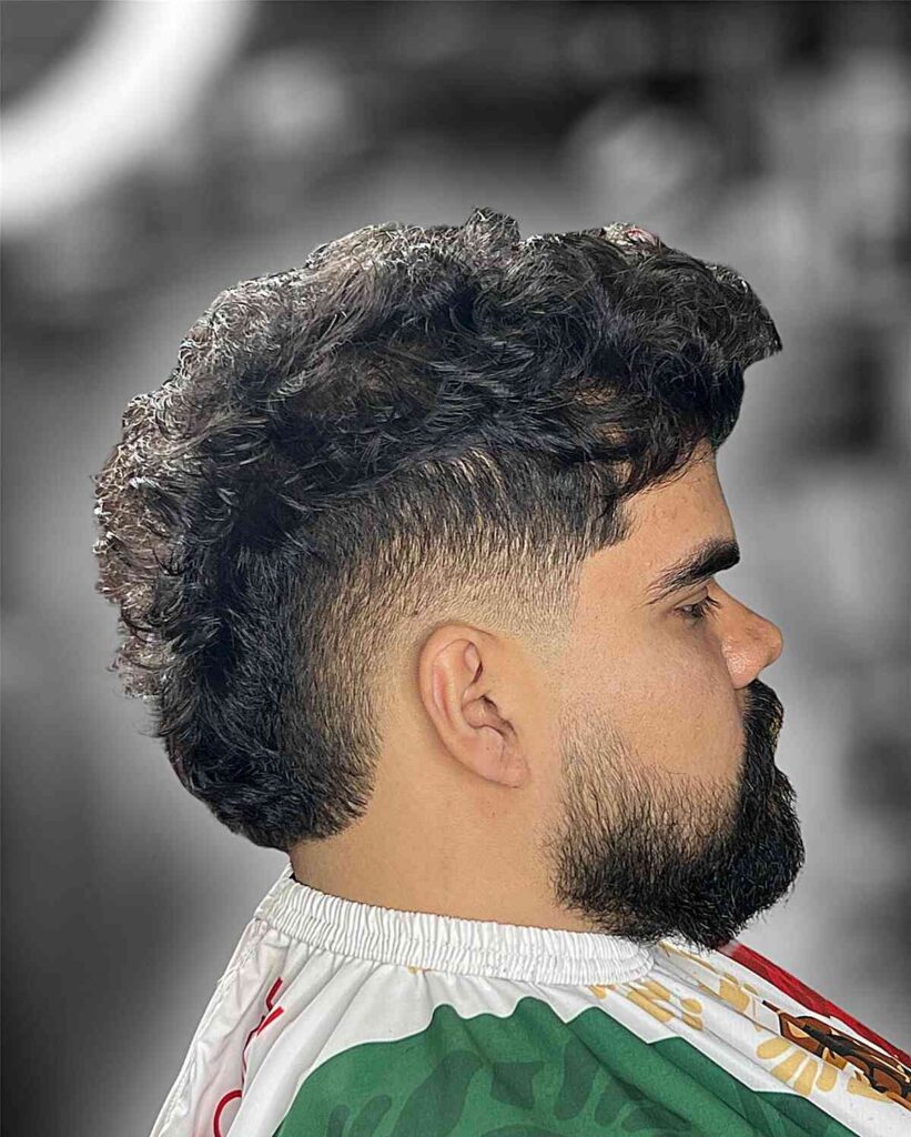 textured mohawk with a low burst fade for mens wavy hair