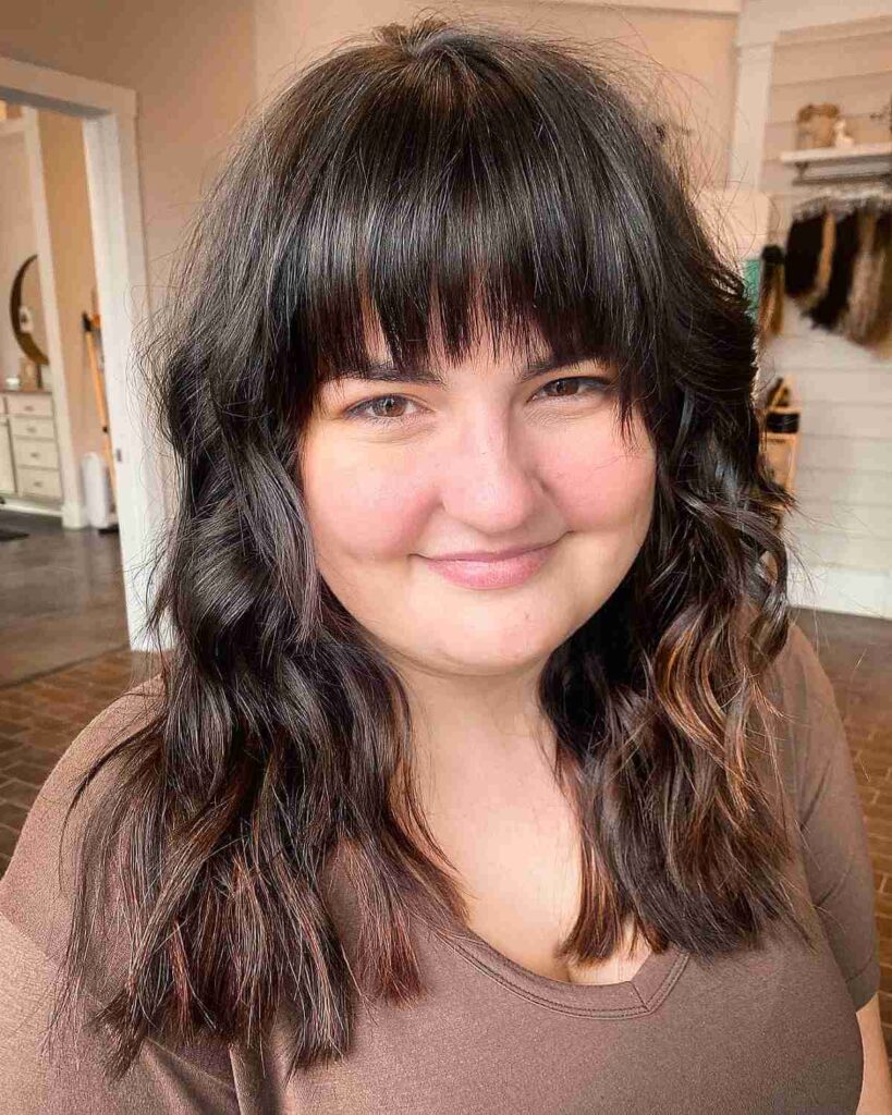 curled mid length hair with straight bangs for round faces